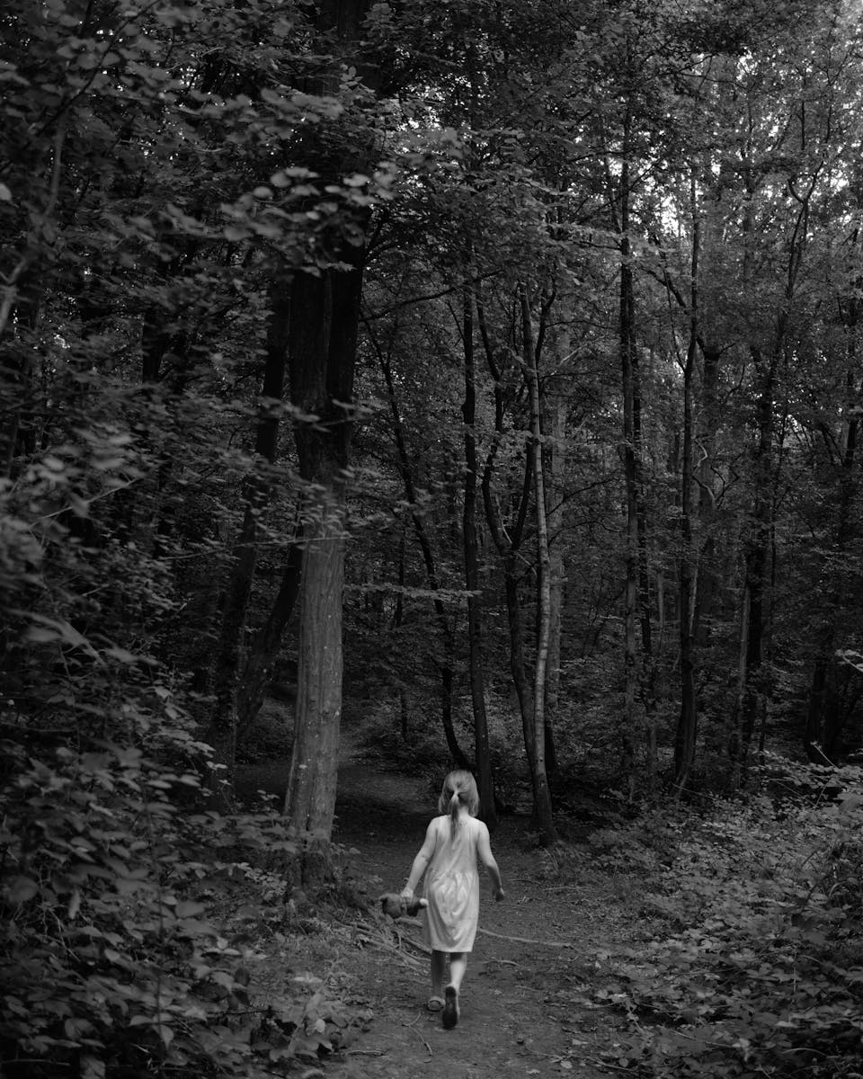 A girl in a white dress walks through a serene forest, capturing a moment of exploration and wonder.