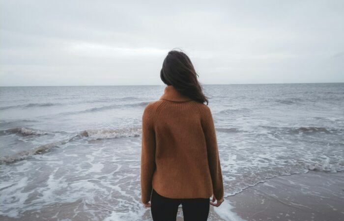 a woman standing on a beach looking out at the ocean