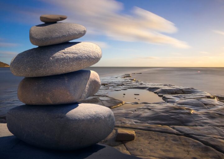 A serene stack of stones on the rocky seashore during a peaceful sunrise, embodying balance and zen.