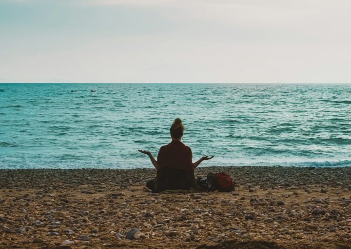 person doing yoga on seashore during daytime