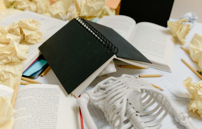 A symbolic display of academic burnout with a notebook, skeleton, and crumpled papers.