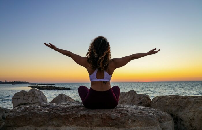 woman sitting on the stone in front of the ocean