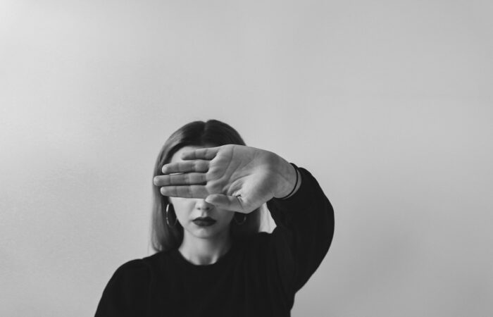 grayscale photo of man in long sleeve shirt covering his face