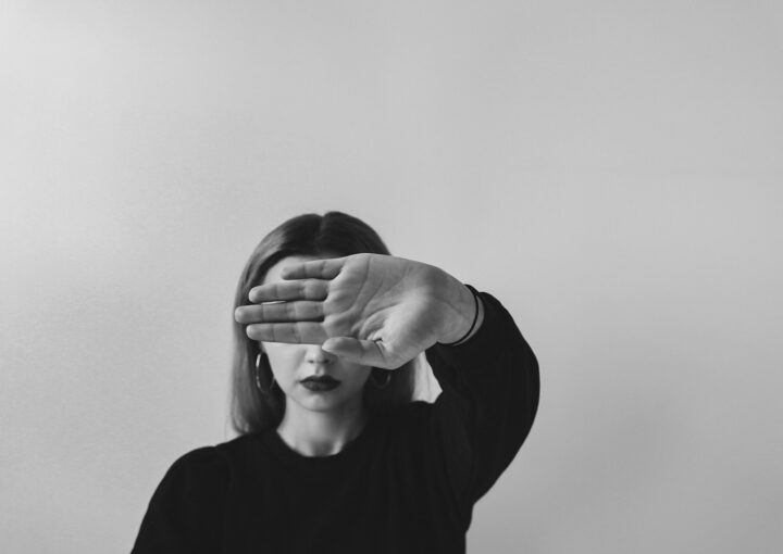 grayscale photo of man in long sleeve shirt covering his face