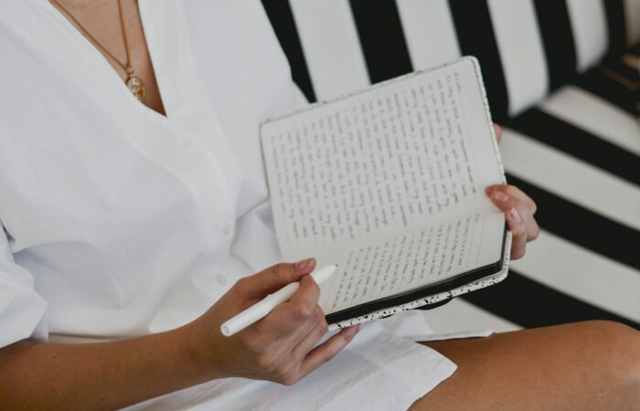 woman in white button up shirt holding white braille paper