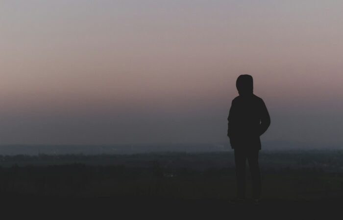 silhouette of man standing on hill during sunset